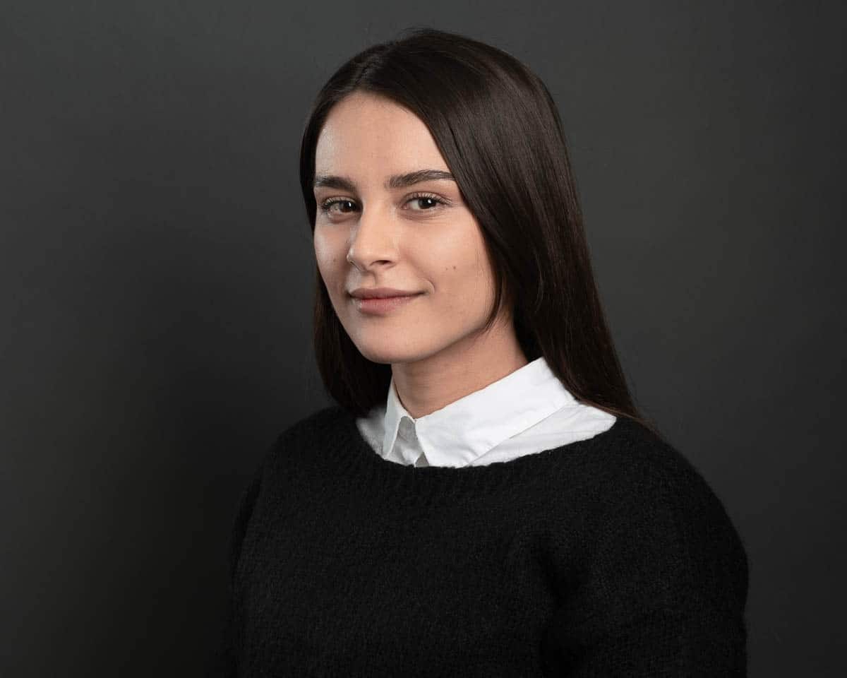Professional headshot of a woman wearing a white shirt and a black sweater